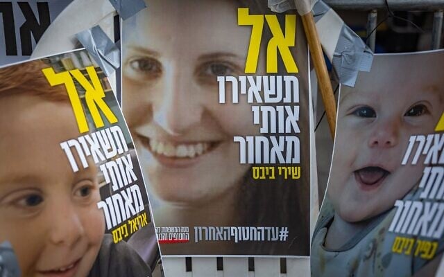 Posters on which "don't leave me behind" is written in Hebrew show Shiri Bibas (C) and her children Kfir (R) and Ariel, outside the Prime Minister's Residence in Jerusalem, February 19, 2025. (Chaim Goldberg/Flash90) Posters on which "don't leave me behind" is written in Hebrew show Shiri Bibas (C) and her children Kfir (R) and Ariel, outside the Prime Minister's Residence in Jerusalem, February 19, 2025. (Chaim Goldberg/Flash90)