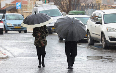 People walk in the rain in the northern Israeli city of Safed, February 20, 2025. (David Cohen/Flash90)