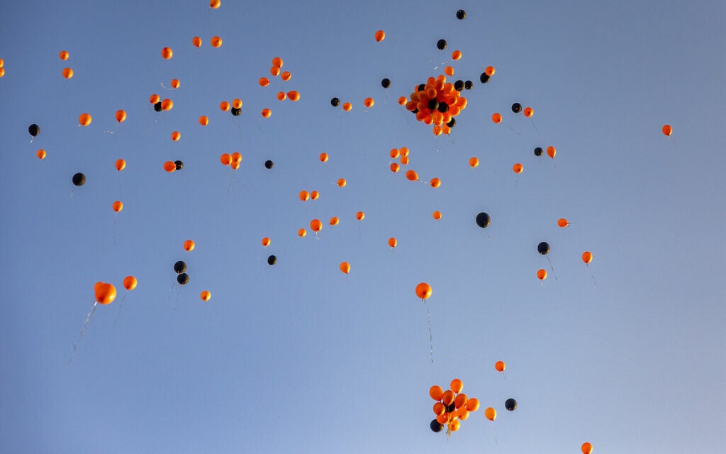 Orange and black helium balloons are sent to the sky during a memorial ceremony for slain Israeli hostages Shiri Bibas and her children Ariel and Kfir, in Jerusalem, February 26, 2025. (Yonatan Sindel/Flash90)