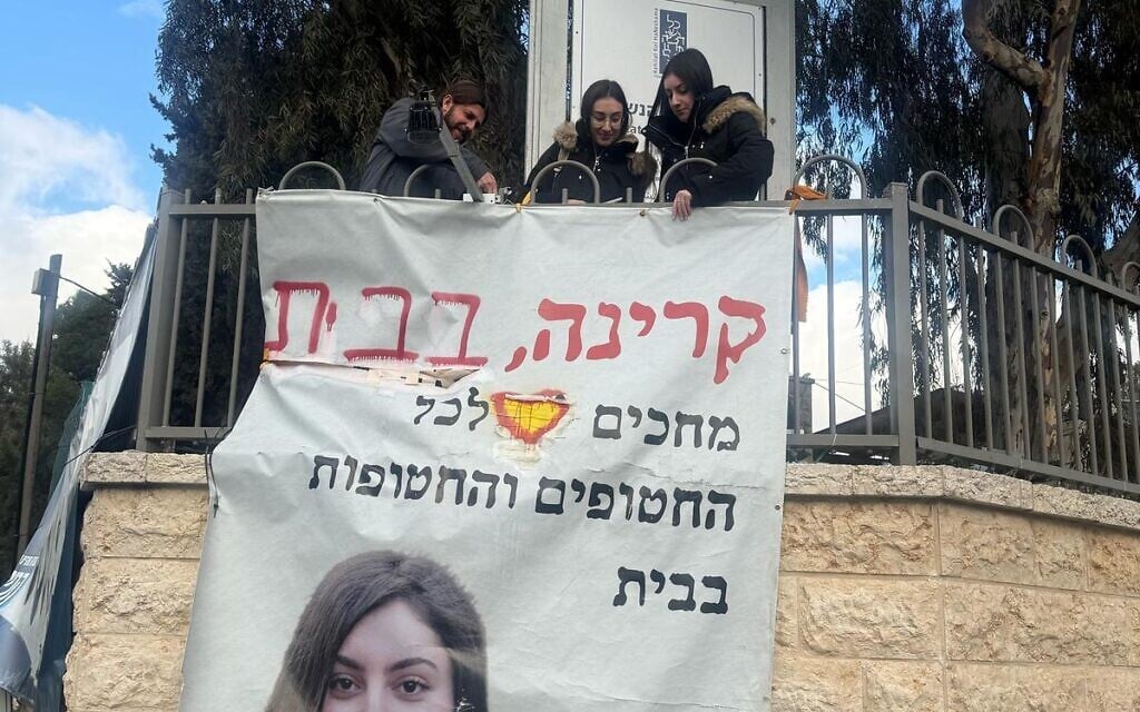 Freed hostage Karina Ariev (right) helps take down a poster calling for her release outside a Jerusalem synagogue, February 24, 2025. (Courtesy)