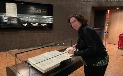Rachel Neiman, a spokesperson at the National Library of Israel, examines a 15th-century manuscript featuring Mezukak Shivatayim ('Distilled Sevenfold'), a previously lost commentary on Maimonines’s Misheh Torah is on display at the National Library of Israel in February 2025. (Rossella Tercatin/Times of Israel)