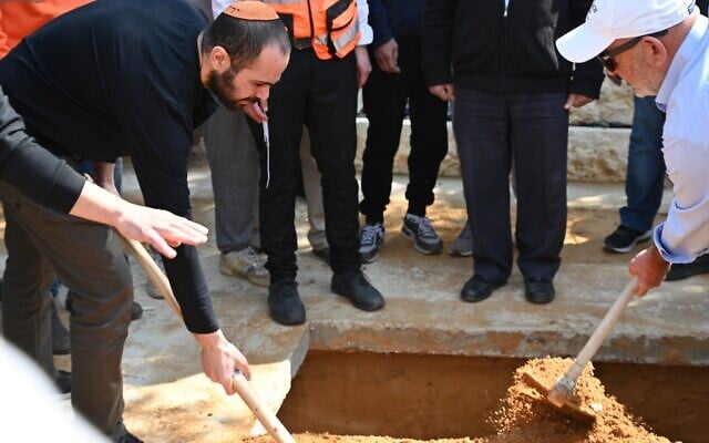 Yarden Bibas covering the coffin of his wife Shiri and sons Ariel and Kfir during the slain hostages' funeral near Kibbutz Nir Oz, February 26, 2025. (Eitan Uner/Hostages and Missing Families Forum)