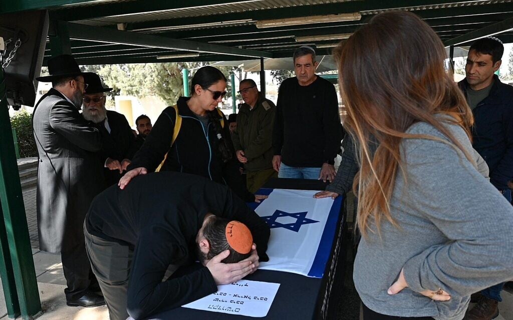 Yarden Bibas cries on the coffin of his wife Shiri and sons Ariel and Kfir during the slain hostages' funeral near Kibbutz Nir Oz, February 26, 2025. (Eitan Uner/Hostages and Missing Families Forum)