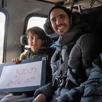 Freed hostage Tal Shoham and his son Naveh on a helicopter en route to a hospital after his release, February 22, 2025 (IDF)