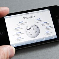 An illustrative image of a person looking at Wikipedia on their phone. (iStock/pressureUA)