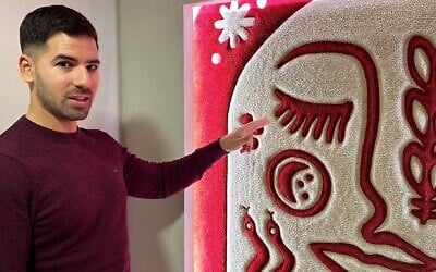 Harel Kopelman shows off a traditional Albanian motif at the entrance to his Albanian Night exhibit in Tirana. (Larry Luxner/ JTA)