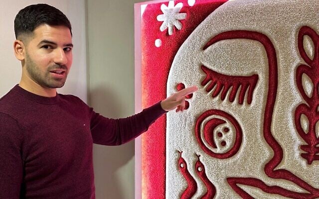 Harel Kopelman shows off a traditional Albanian motif at the entrance to his Albanian Night exhibit in Tirana. (Larry Luxner/ JTA)