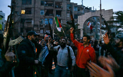 Local residents cheer as they gather on a street in the Damascus suburb of Jaramana on December 8, 2024. (LOUAI BESHARA / AFP)