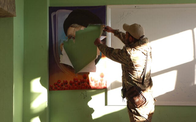 A Syria rebel fighter rips a portrait of slain Hezbollah leader Hassan Nasrallah, in a building reportedly used by Lebanon's Hezbollah terror group, in the town of in Qusayr in Syria's central Homs province, on December 15, 2024. (Photo by AAREF WATAD / AFP) A Syria rebel fighter rips a portrait of slain Hezbollah leader Hassan Nasrallah, in a building reportedly used by Lebanon's Hezbollah terror group, in the town of in Qusayr in Syria's central Homs province, on December 15, 2024. (Photo by AAREF WATAD / AFP)