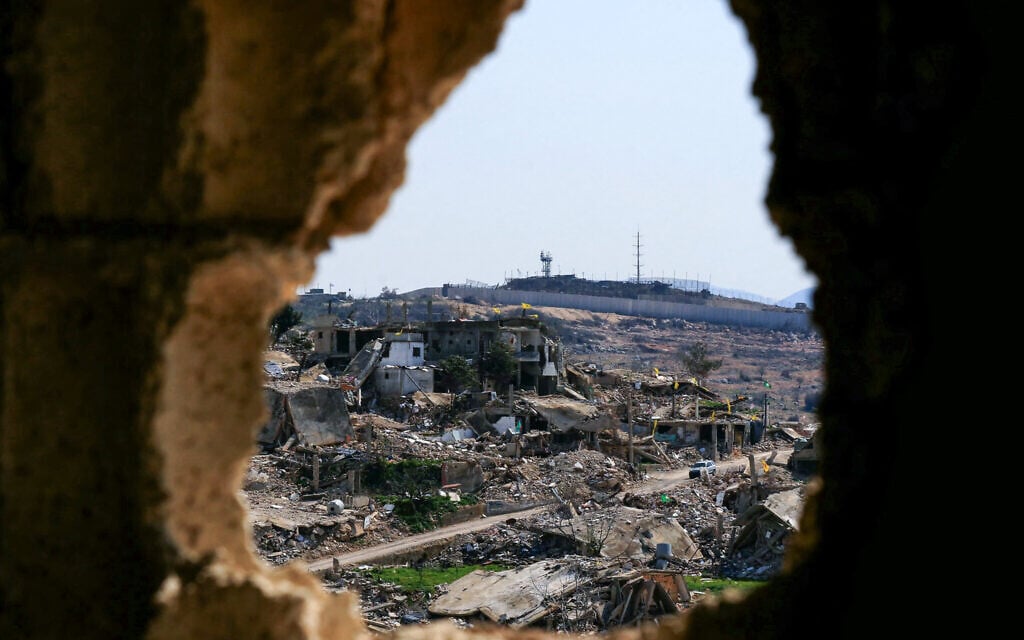 A vehicle drives past buildings destroyed in Israeli strikes during the latest war with Hezbollah, near the border wall in the southern Lebanese village of Ramia, March 5, 2025. (Photo by Mahmoud ZAYYAT / AFP)