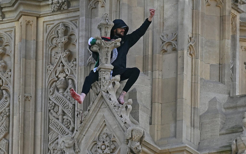 A protester holding a Palestinian flag gestures from the side of the Elizabeth Tower, commonly known by the name of the clock's bell 'Big Ben,' in central London, March 8, 2025. (Ben Stansall/AFP)