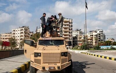 Security forces loyal to the interim Syrian government attach a turret atop an armored vehicle parked along a road in Syria's western city of Latakia, March 9, 2025. (Omar Haj Kadour / AFP)