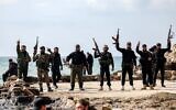 Members of security forces loyal to the interim Syrian government pose together with their firearms as they stand by the Mediterranean sea coast in Syria's western city of Latakia on March 9, 2025. (OMAR HAJ KADOUR / AFP)