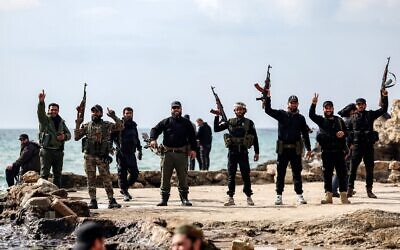 Members of security forces loyal to the interim Syrian government pose together with their firearms as they stand by the Mediterranean sea coast in Syria's western city of Latakia on March 9, 2025. (OMAR HAJ KADOUR / AFP)