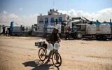 A youth pushes a bicycle loaded with filled-up water containers outside the Southern Gaza Desalination plant, which stopped working after Israel cut off electricity to the Gaza Strip, in Deir el-Balah in the center of the Palestinian territory on March 10, 2025. (Eyad BABA/AFP)