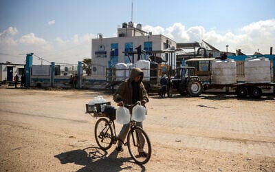 A youth pushes a bicycle loaded with filled-up water containers outside the Southern Gaza Desalination plant, which stopped working after Israel cut off electricity to the Gaza Strip, in Deir el-Balah in the center of the Palestinian territory on March 10, 2025. (Eyad BABA/AFP)