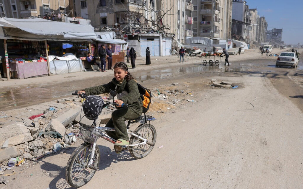 A Palestinian girl rides a bicycle west of Jabalia in the northern Gaza Strip on March 11, 2025. (BASHAR TALEB / AFP)