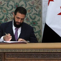 Syria's interim President Ahmad al-Sharaa signs the country's constitutional declaration, which will be enforced throughout a five-year transitional period, at the presidential palace in Damascus on March 13, 2025. (Bakr ALKASEM / AFP)
