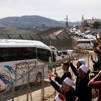 Druze people wave near a border barrier in the northern Israeli village of Majdal Shams, as buses transporting visiting Druze men from Syria arrive, on March 14, 2025. (Jalaa MAREY / AFP)