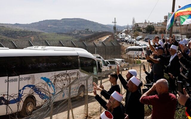 Druze people wave near a border barrier in the northern Israeli village of Majdal Shams, as buses transporting visiting Druze men from Syria arrive, on March 14, 2025. (Jalaa MAREY / AFP) Druze people wave near a border barrier in the northern Israeli village of Majdal Shams, as buses transporting visiting Druze men from Syria arrive, on March 14, 2025. (Jalaa MAREY / AFP)