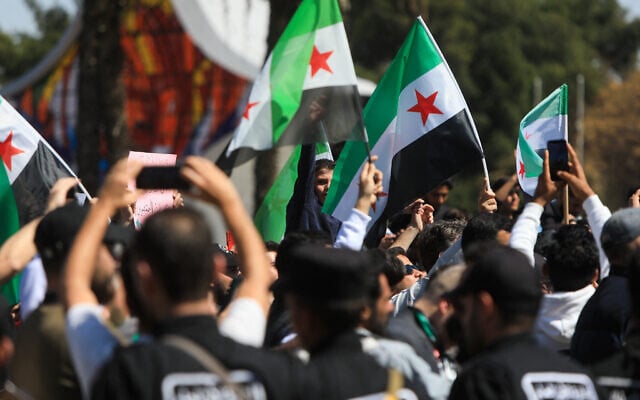 Syrian security forces stand guard as people chant and wave national flags amid celebrations on the fourteenth anniversary of the Syrian uprising, at a rally in Umayyad Square in Damascus on March 15, 2025. (Bakr AlKasem/AFP) Syrian security forces stand guard as people chant and wave national flags amid celebrations on the fourteenth anniversary of the Syrian uprising, at a rally in Umayyad Square in Damascus on March 15, 2025. (Bakr AlKasem/AFP)