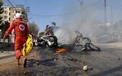 A Red Cross rescuer walks toward a burning car after it was hit by an Israeli strike in a southern Lebanese village on March 15, 2025, in which one person was reportedly killed. (Rabih DAHER / AFP)