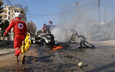 A Red Cross rescuer walks toward a burning car after it was hit by an Israeli strike in a southern Lebanese village on March 15, 2025, in which one person was reportedly killed. (Rabih DAHER / AFP)