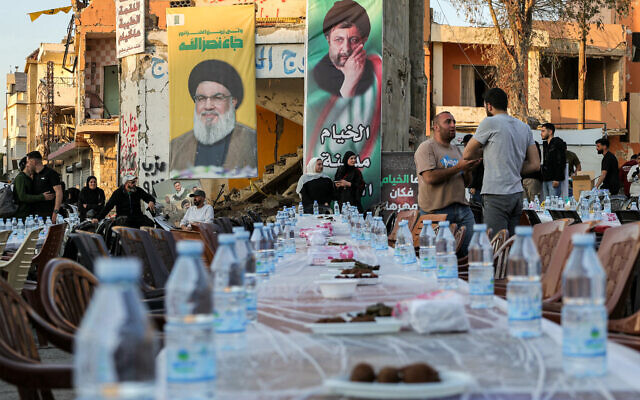 Pictures of Hassan Nasrallah, the slain former leader of Hezbollah, and other killed fighters are displayed as people arrive for and prepare a mass fast-breaking iftar meal amid the rubble of destroyed buildings in Lebanon's southern village of Khiam near the border with Israel on March 15, 2025 during the Muslim holy month of Ramadan. (Photo by Rabih DAHER / AFP) Pictures of Hassan Nasrallah, the slain former leader of Hezbollah, and other killed fighters are displayed as people arrive for and prepare a mass fast-breaking iftar meal amid the rubble of destroyed buildings in Lebanon's southern village of Khiam near the border with Israel on March 15, 2025 during the Muslim holy month of Ramadan. (Photo by Rabih DAHER / AFP)
