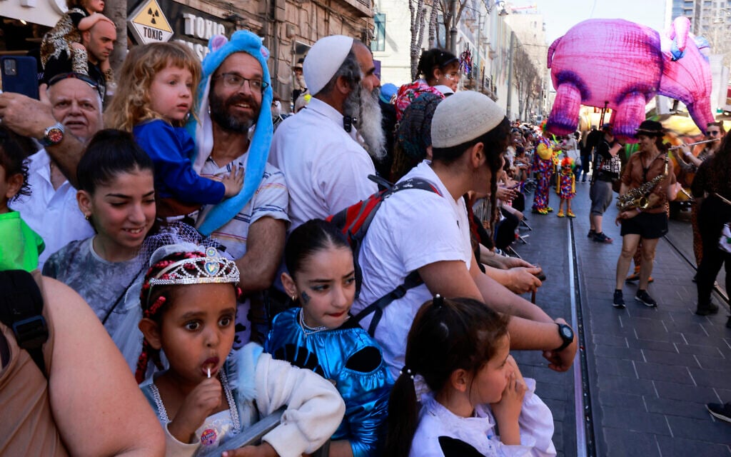 People to watch a parade organized as part of the Purim feast celebrations, in the Jerusalem  on March 16, 2025.  (Photo by Menahem Kahana / AFP)