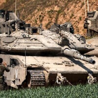 An Israeli army soldier signals for the driver of a Merkava battle tank attempting to park at a position in southern Israel along the northern Gaza Strip on March 18, 2025. (Menahem Kahana / AFP)