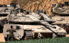 An Israeli army soldier signals for the driver of a Merkava battle tank attempting to park at a position in southern Israel along the northern Gaza Strip on March 18, 2025. (Menahem Kahana / AFP)