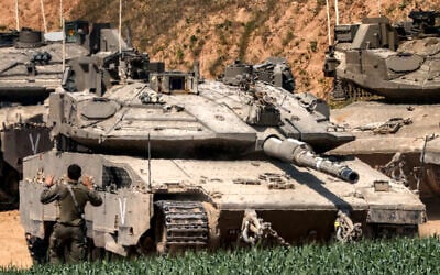 An Israeli army soldier signals for the driver of a Merkava battle tank attempting to park at a position in southern Israel along the northern Gaza Strip on March 18, 2025. (Menahem Kahana / AFP)