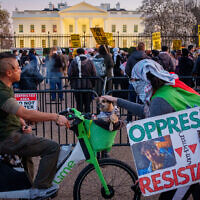 A protester, with a sign that employs the inverted red triangle used in Hamas propaganda to indicate a target, stops to pet a dog as demonstrators rally outside the White House, after Israel resumes airstrikes in Gaza amid its war against Hamas, on March 18, 2025. (Andrew Harnik / GETTY IMAGES NORTH AMERICA / Getty Images via AFP)