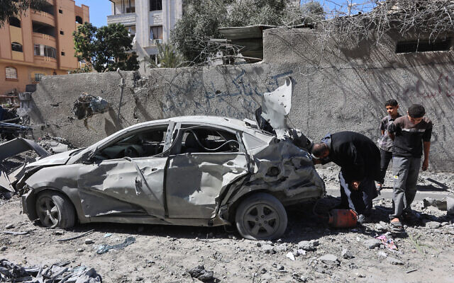 Palestinians inspect a destroyed car after an Israeli strike in Gaza City on March 19, 2025. (Omar AL-QATTAA / AFP)