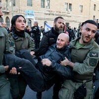 National Guard officers, distinguishable from standard Border Police by patches with the force's insignia on their uniform sleeves, carry away a protester during a demonstration against Prime Minister Benjamin Netanyahu and calling for an end to the war in Gaza on March 19, 2025. (Menahem Kahana/AFP)
