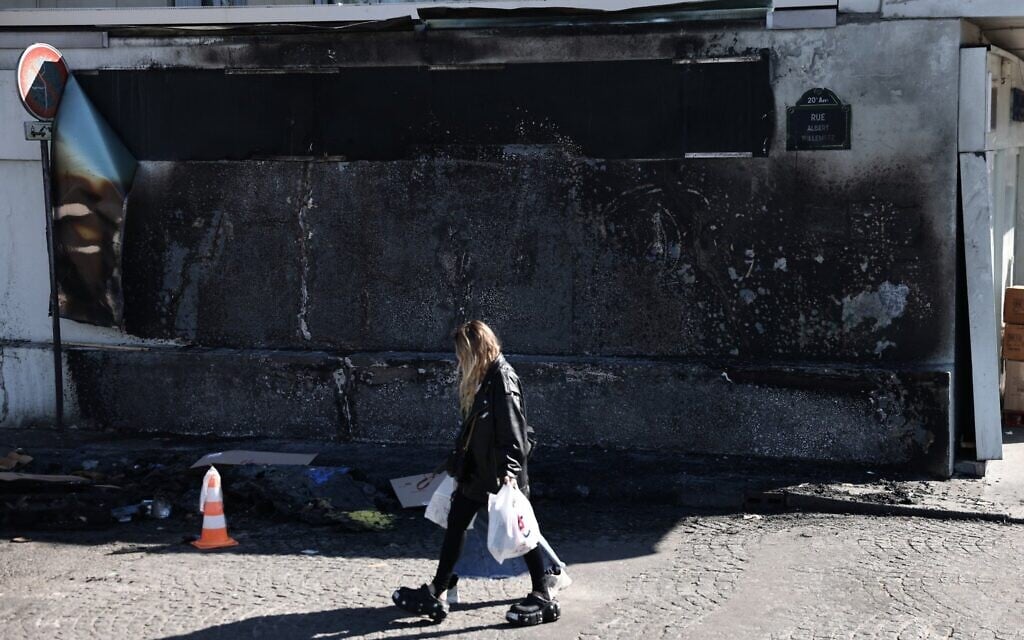 A woman walks by the Hypercacher Jewish supermarket after its facade was set ablaze overnight in Paris on March 20, 2025 (Thibaud MORITZ / AFP)