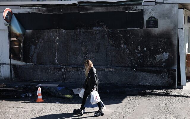 A woman walks by the Hypercacher Jewish supermarket after its facade was set ablaze overnight in Paris on March 20, 2025 (Thibaud MORITZ / AFP)
