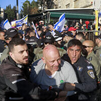 An anti-government demonstrator is seen with a cut on his head being escorted by security forces during scuffles outside the Prime Minister's Residence in Jerusalem on March 23, 2025. (Menahem Kahana / AFP)