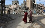 Palestinians walk past debris of buildings destroyed during the Israel-Hamas war, in Gaza City on March 28, 2025. (Omar Al-Qattaa / AFP)