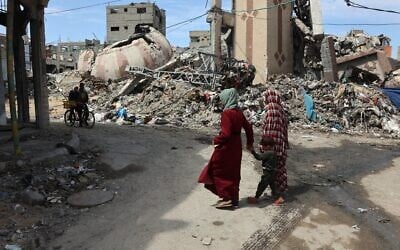 Palestinians walk past debris of buildings destroyed during the Israel-Hamas war, in Gaza City on March 28, 2025. (Omar Al-Qattaa / AFP)