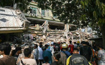 People look on as teams of rescue workers attempt to free residents trapped under the rubble of the destroyed Sky Villa Condominium development in Mandalay on March 29, 2025, a day after an earthquake struck central Myanmar. (Sai Aung MAIN / AFP)