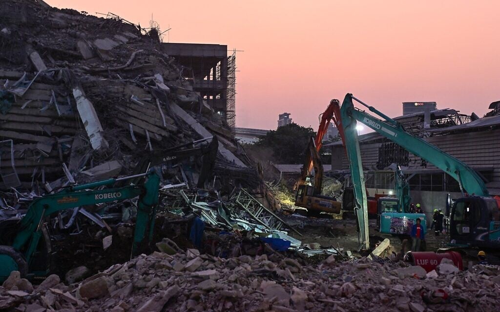Heavy construction equipment is used to find people trapped in the rubble at the site of an under-construction building collapse as the sun sets in Bangkok on March 29, 2025, a day after an earthquake struck central Myanmar and Thailand. (MANAN VATSYAYANA / AFP)