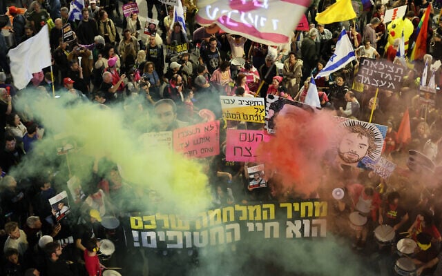 Manifestantes levantam cartazes e acendem sinalizadores durante um protesto antigovernamental pedindo ações para garantir a libertação de reféns israelenses, Tel Aviv, em 29 de março de 2025. (Jack GUEZ / AFP)