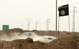 FILE - Islamic State militants pass a checkpoint bearing the group's trademark black flag in the village of Maryam Begg in Kirkuk, 180 miles north of Baghdad, Iraq, Sept. 29, 2014. (AP Photo/Hadi Mizban, File)