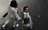 An Iranian woman without a mandatory headscarf, or hijab, flashes a victory sign as she walks at the old main bazaar of Tehran, Iran, June 13, 2024. (AP Photo/Vahid Salemi, File)