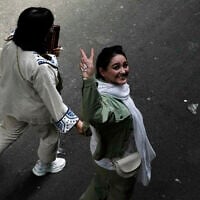 An Iranian woman without a mandatory headscarf, or hijab, flashes a victory sign as she walks at the old main bazaar of Tehran, Iran, June 13, 2024. (AP Photo/Vahid Salemi, File)