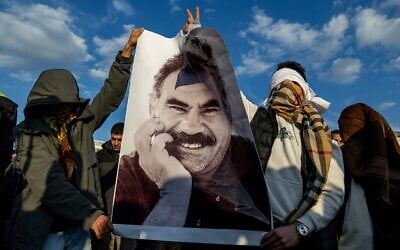 Youngsters hold a photograph of the jailed leader of the rebel Kurdistan Workers' Party, or PKK, Abdullah Ocalan as they gather to watch live on a tv screen a Pro-Kurdish Peoples' Equality and Democracy Party, or DEM, delegation members releasing an statement from Ocalan, in Diyarbakir, Turkey, Feb. 27, 2025. (AP Photo/Metin Yoksu)