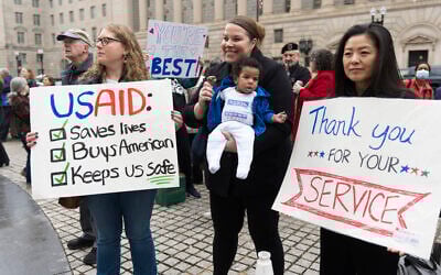 United States Agency for International Development (USAID) supporters hold banners as USAID workers retrieve their personal belongings from the USAID's headquarters in Washington, February 27, 2025. (AP/Manuel Balce Ceneta)