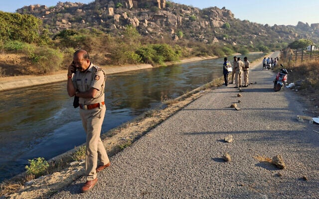 A police officer speaks on his mobile phone at the scene as he and colleagues search for the male travelers who were pushed into the canal by three men accused of gang-raping two women, in Koppal district of southern state of Karnataka, India, Friday, March 7, 2025. (AP Photo)