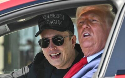 US President Donald Trump, right, and Tesla CEO Elon Musk speak to reporters as they sit in a Tesla vehicle on the South Lawn of the White House in Washigton, March 11, 2025. (Pool via AP)